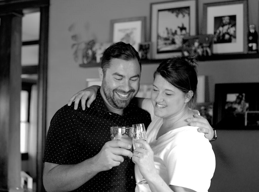 This is a photo by Kat Stano of a cute couple in their home, toasting their glasses.