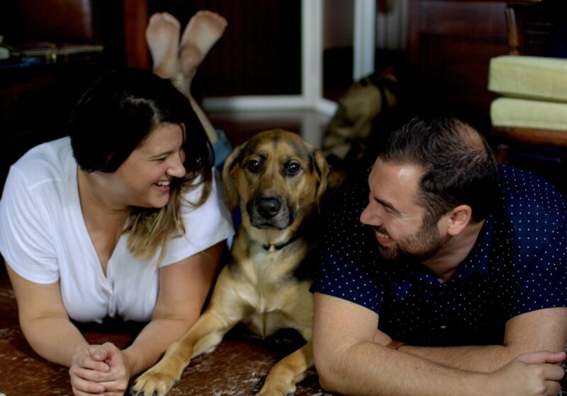 This is a photo by Kat Stano of a young couple lounging on the floor in their stylish home, with their dog, looking at vintage vinyl records.