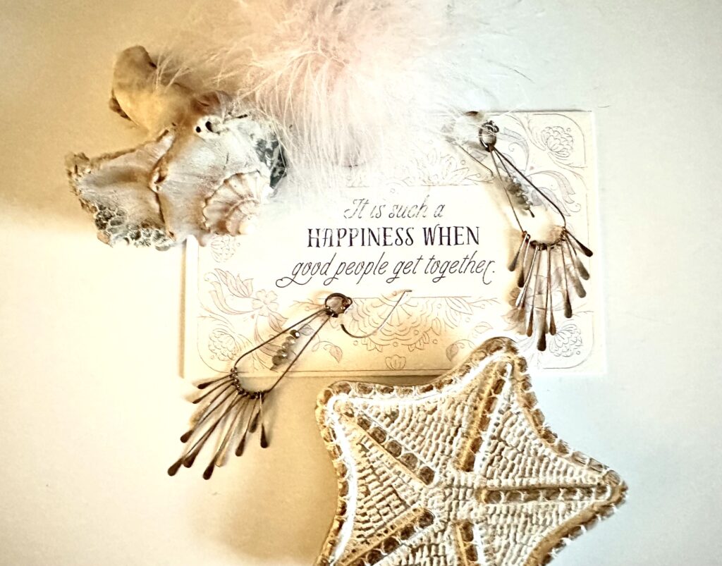 This is a photo by Kat Stano of a jewelry flat lay with a pair of earrings, seashell, feathery accessory, starfish box, and a Jane Austen quote that says, "It is such happiness when good people get together."