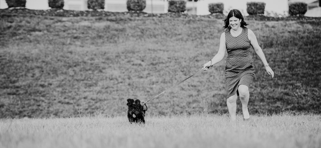 This is a photo by Tonya Dean Photography of Kat Stano running in a field with her dog Cosette.