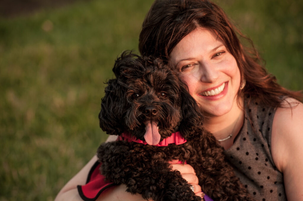 This is a photo by Tonya Dean Photography of Kat Stano hugging her dog Cosette. Cosette has her tongue out.