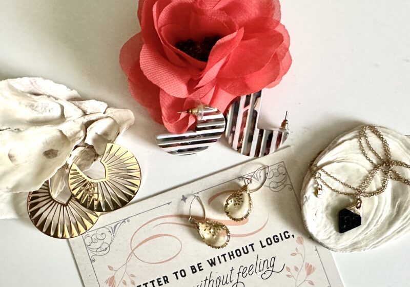 This is a photo by Kat Stano of Starfish Project jewelry, two seashells, a flower, and a Jane Austen quote that says, "Better to be without logic than without feeling."