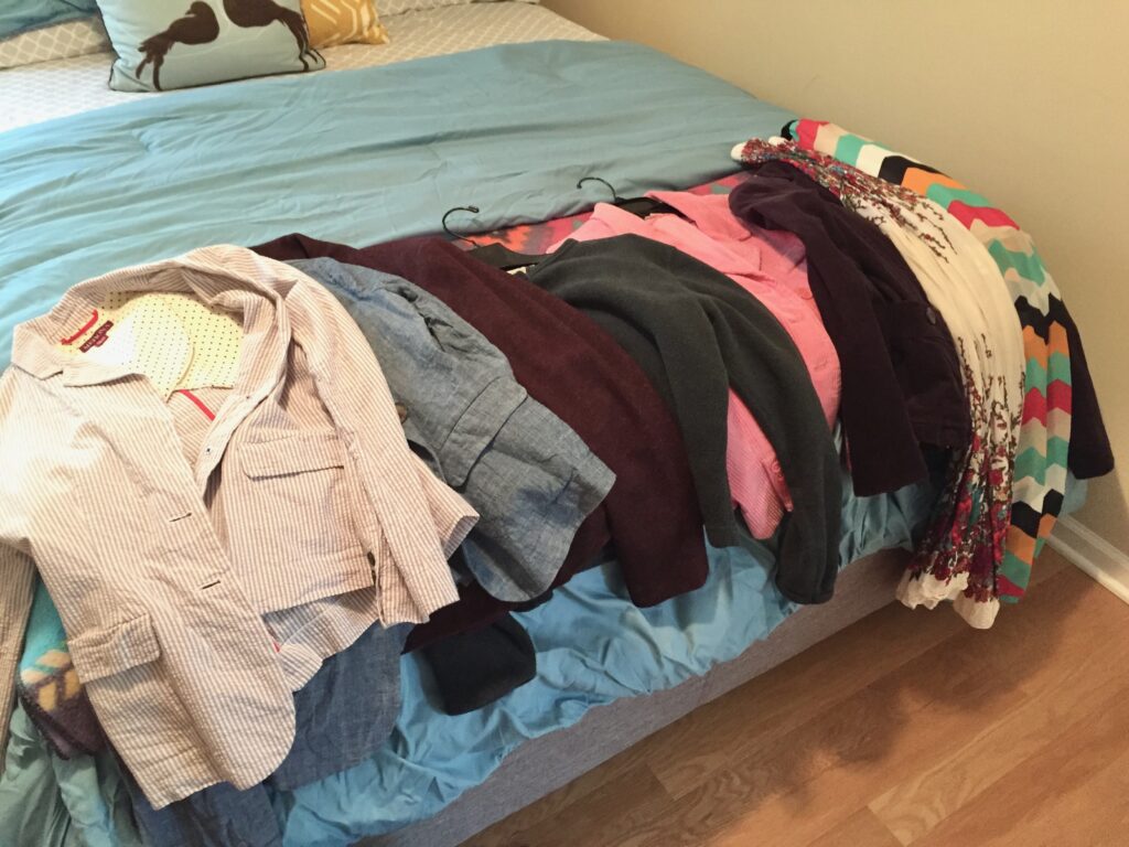 This is a photo of clothes on a bed that are going to be donated.