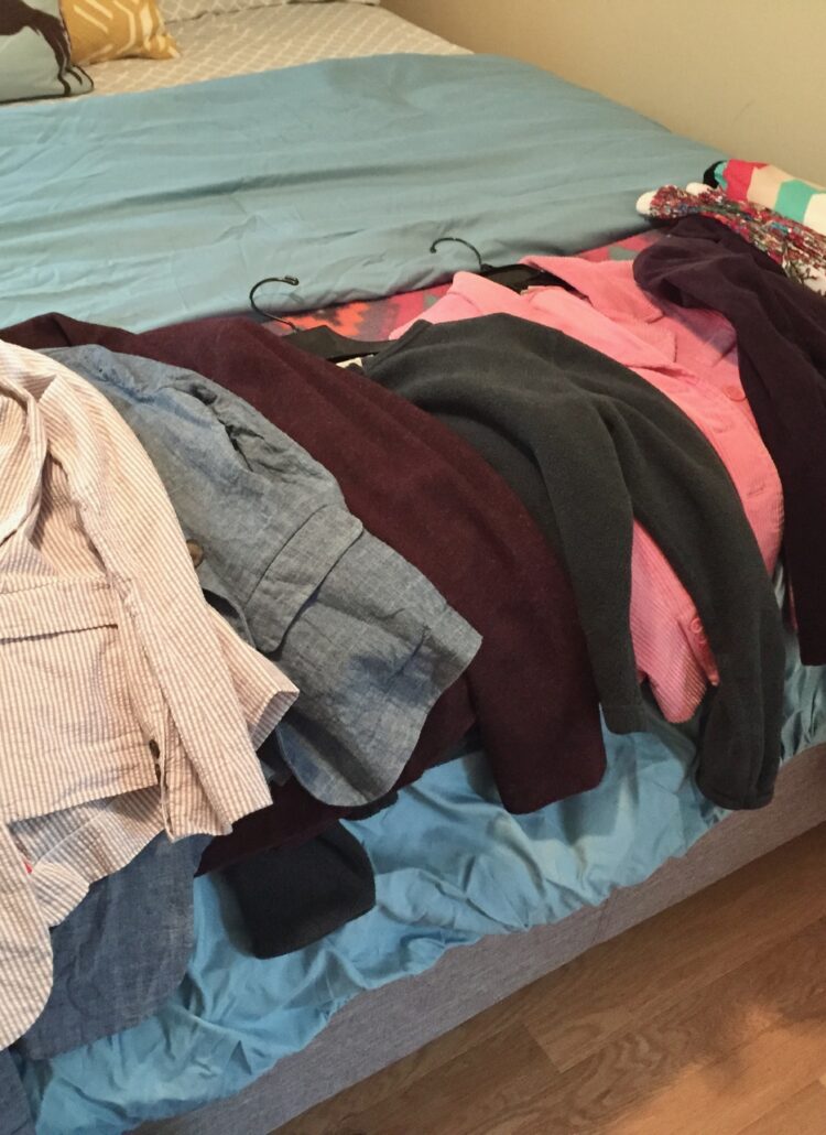 Here is a picture of clothes on a bed that are ready to give away, recycle, or donate.