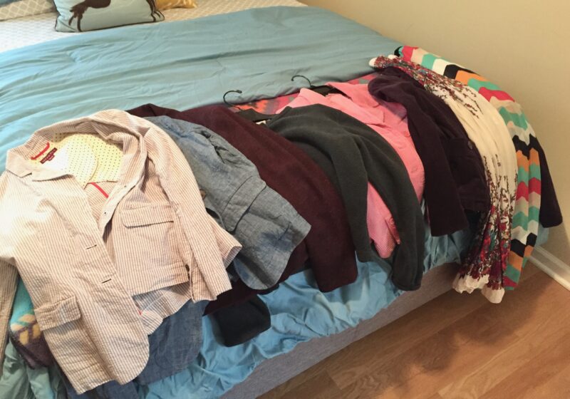 Here is a picture of clothes on a bed that are ready to give away, recycle, or donate.