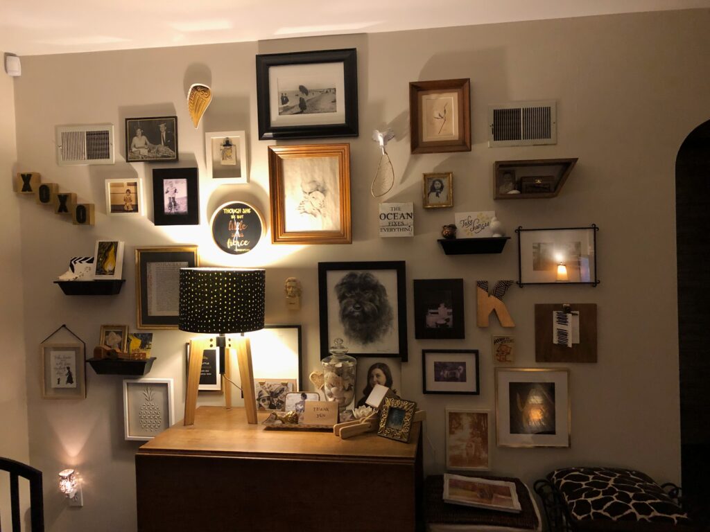 This is a photo of a salon or gallery wall of photos and art in Kat's house.