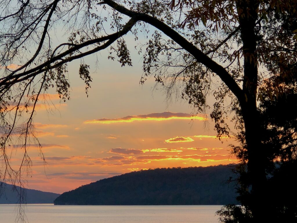 This is a photo of a lake at sunset in East Tennessee with some arching trees in the forefront, demonstrating nature's own zero waste lipstick.