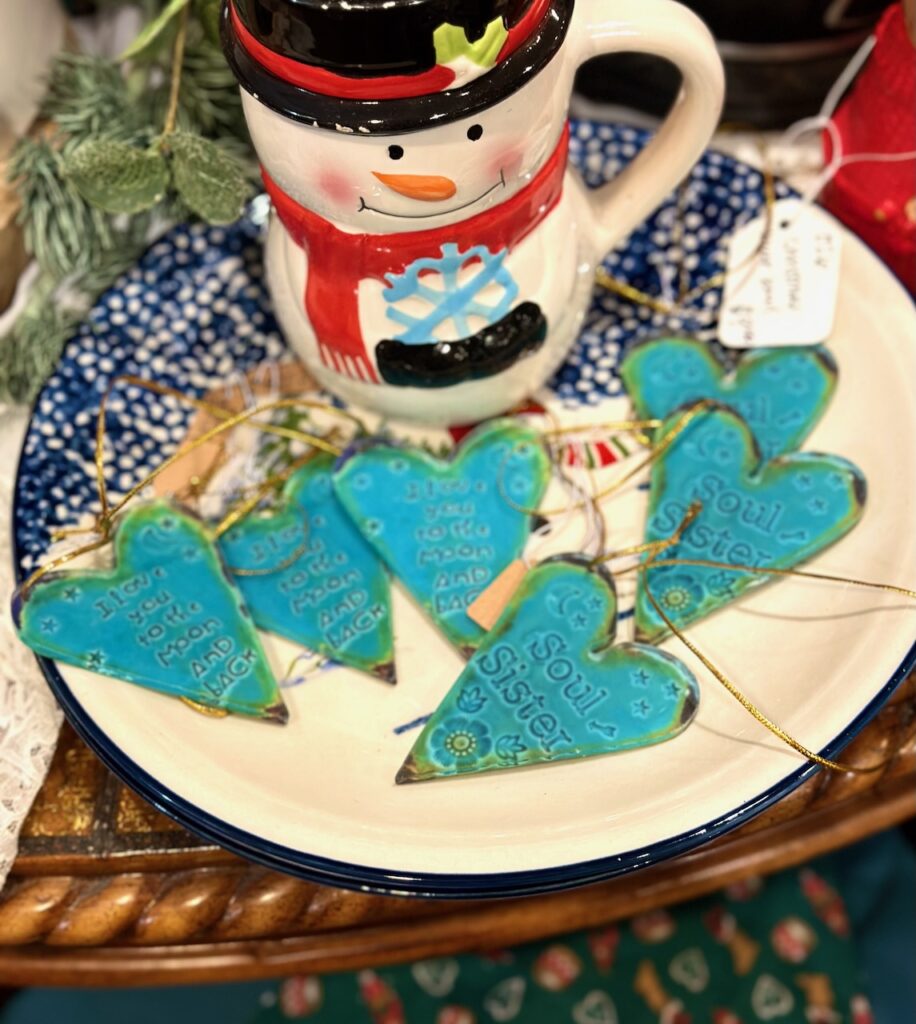 This is a ceramic snowman mug and ceramic turquoise hearts that say "love you to the moon and back" and "soul sister" as examples of holiday decorations for the home.