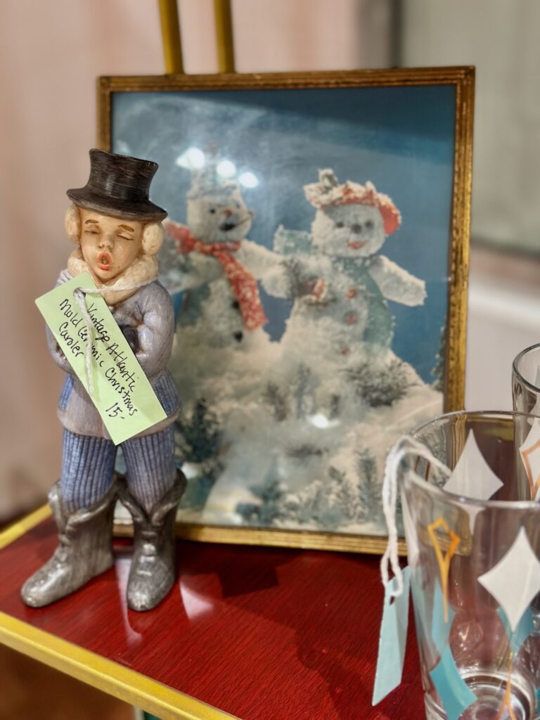 Here is a snowman couple on a greeting card that's been framed and is by a vintage caroler figurine to show unique christmas greeting cards.