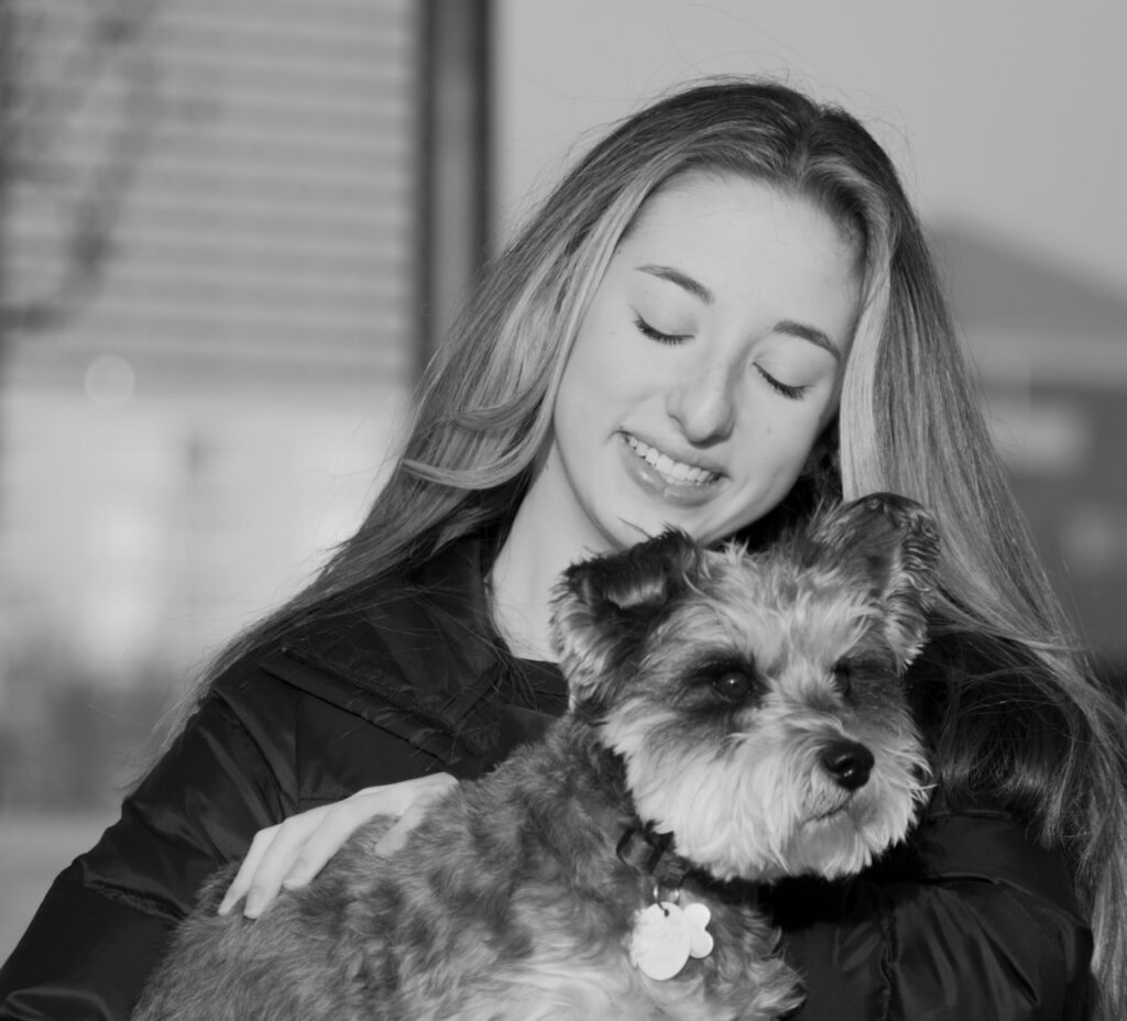 This is a photo by Kat Stano of a girl holding her schnauzer dog with love as an illustration of a good person definition.