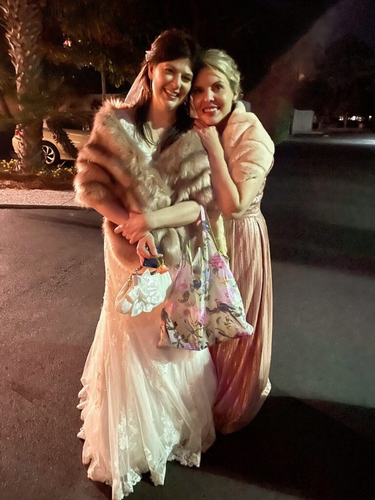 This is Kat and her best friend posing with the reusable shopping tote that has a bird, butterfly, and floral theme as nature wedding favors.