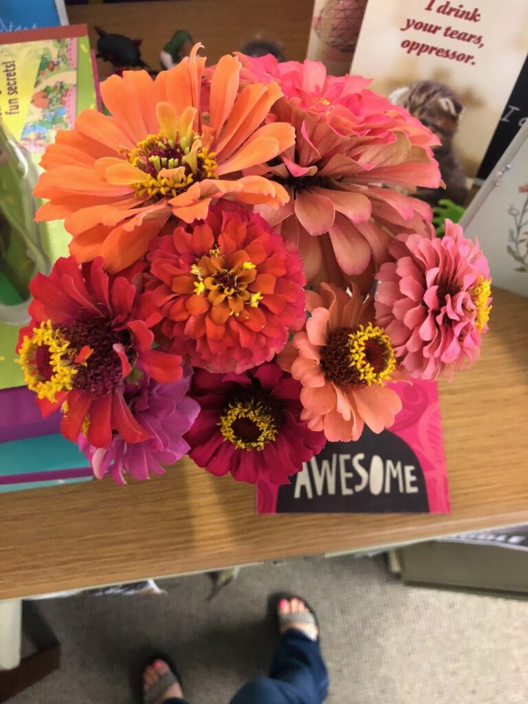 This is a bouquet of colorful flowers with a card that says, "Awesome" and a funny cat photo in the background that says, "I drink your tears, oppressor" to describe signs of a kind person psychology.