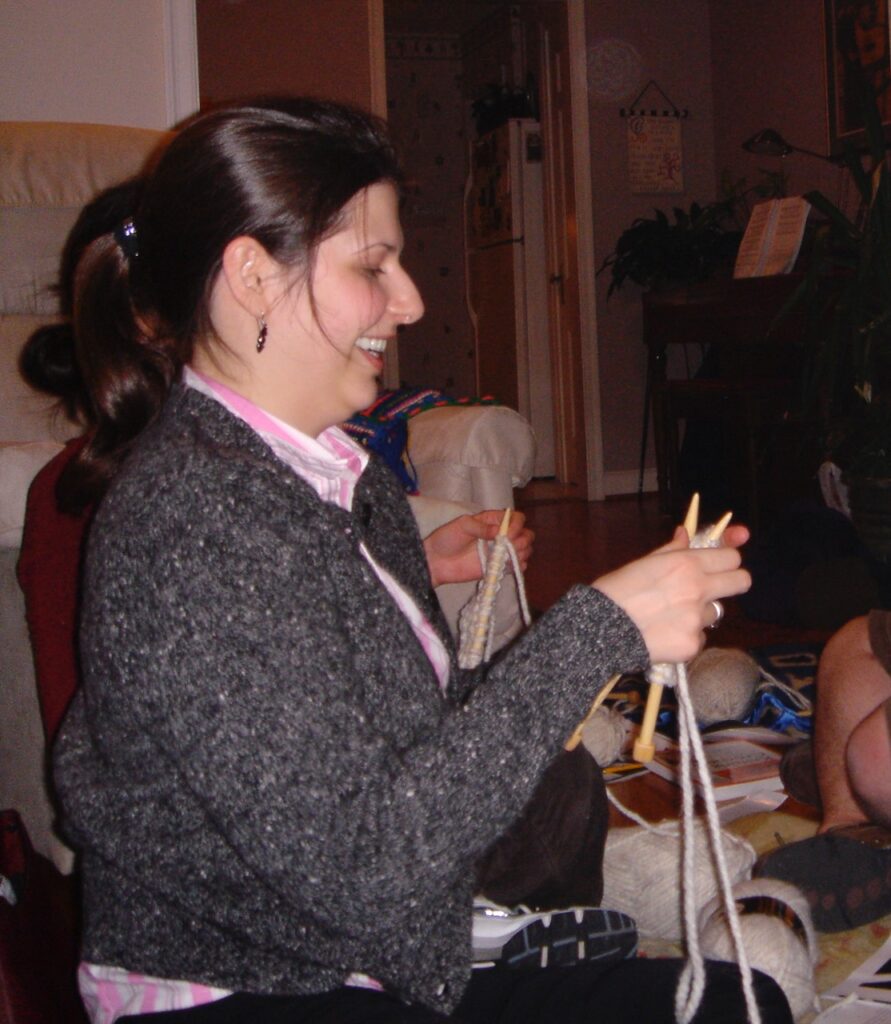 This is Kat as a young woman knitting a scarf at a party to show an example of a soft hearted woman.