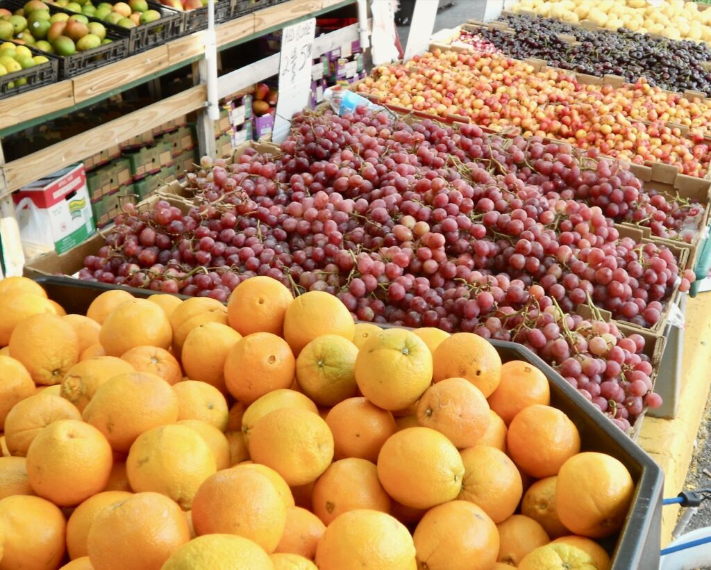 This is a farmer's market stand with oranges, grapes, cherries, and mangoes to talk about composting facts.