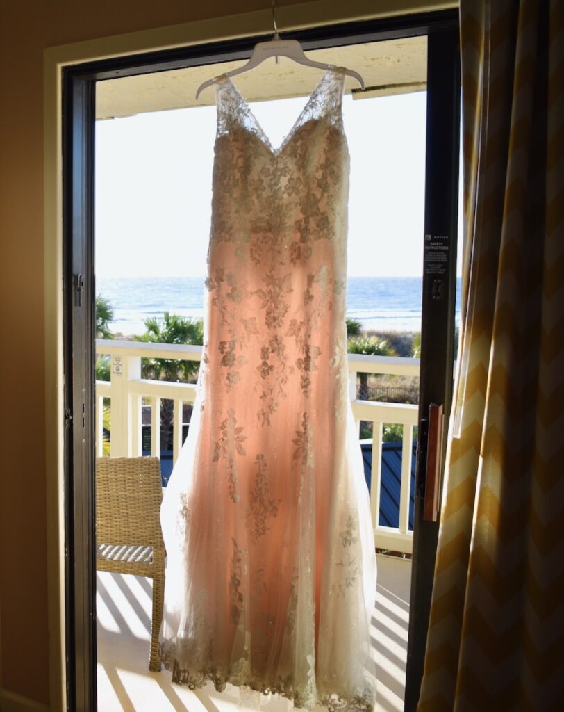 This is Kat's wedding dress hanging in the doorway in front of the ocean to discuss eco friendly wedding dress.