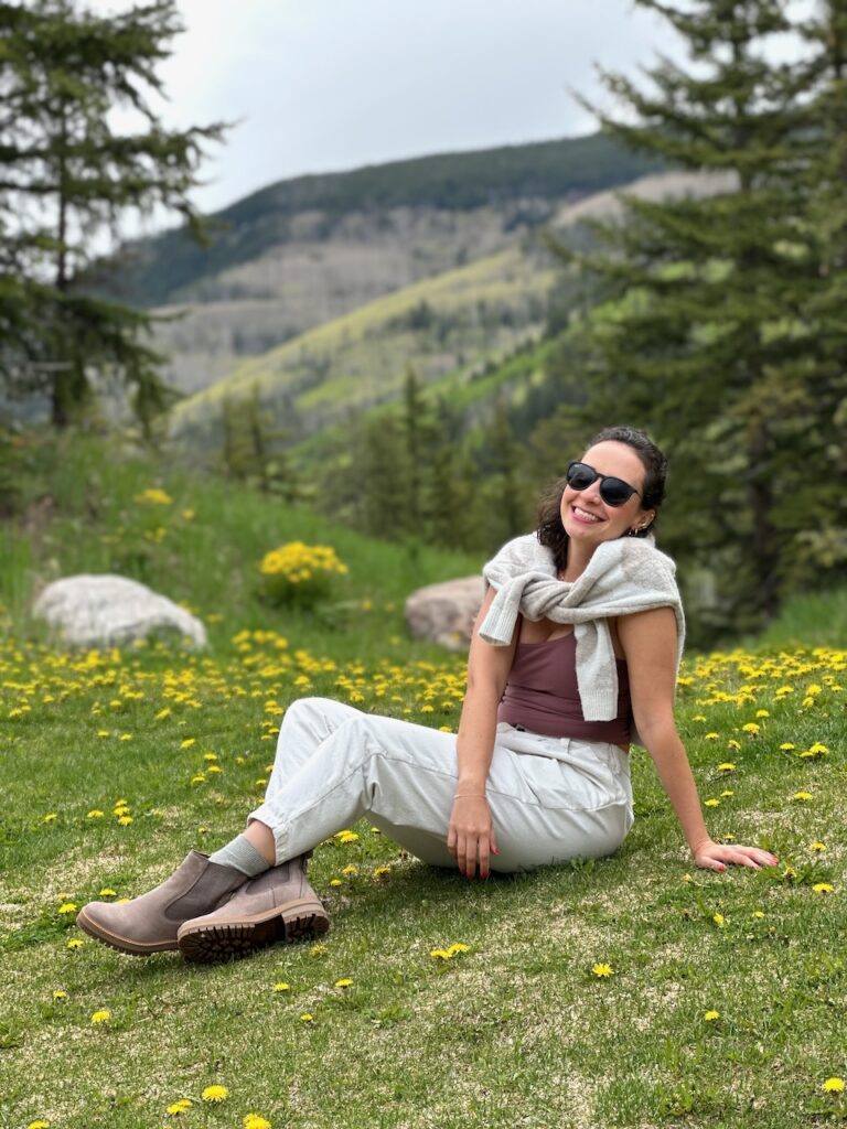 This is Kat's friend sitting in a field of dandelions in front of the mountains in Colorado to show the pros of composting.