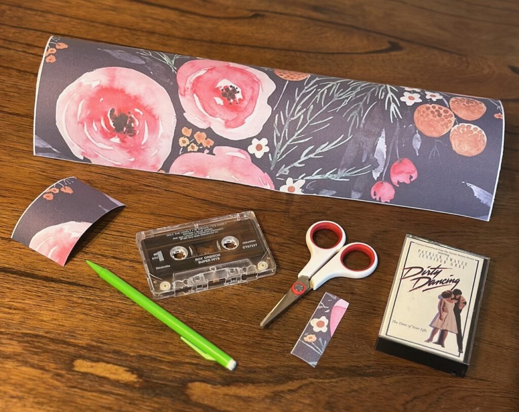 This is a roll of removable wallpaper, plus little smaller pieces, a Roy Orbison cassette tape, a Dirty Dancing cassette tape case, scissors, and a mechanical pencil to share diy unique business card holders for desk.