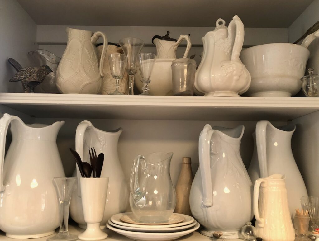This is a collection of vintage white ironstone china, glassware, and small collectibles like a bird figurine to show how to do a low buy year.