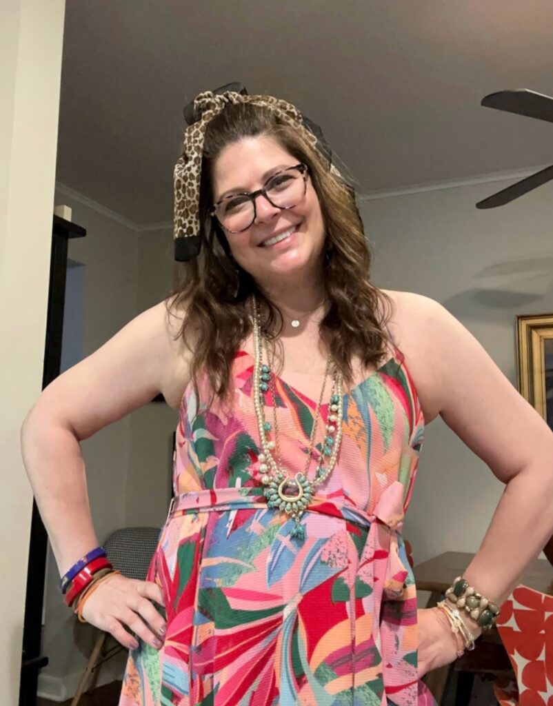This is Kat wearing a sleeveless colorful dress, leopard print scarf, lots of necklaces, and '80s bracelets and bangles for a Cyndi Lauper concert to demonstrate low buying.