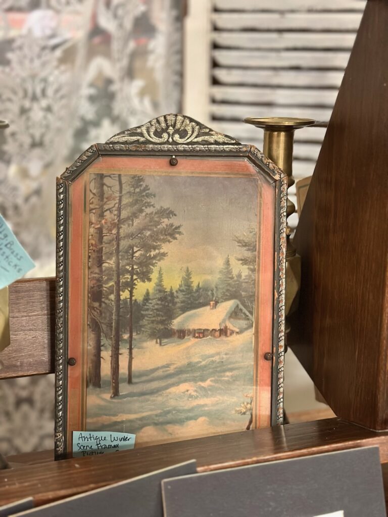 This is a print of a cabin in the snowy woods in a fancy vintage frame to show eco friendly christmas decor.
