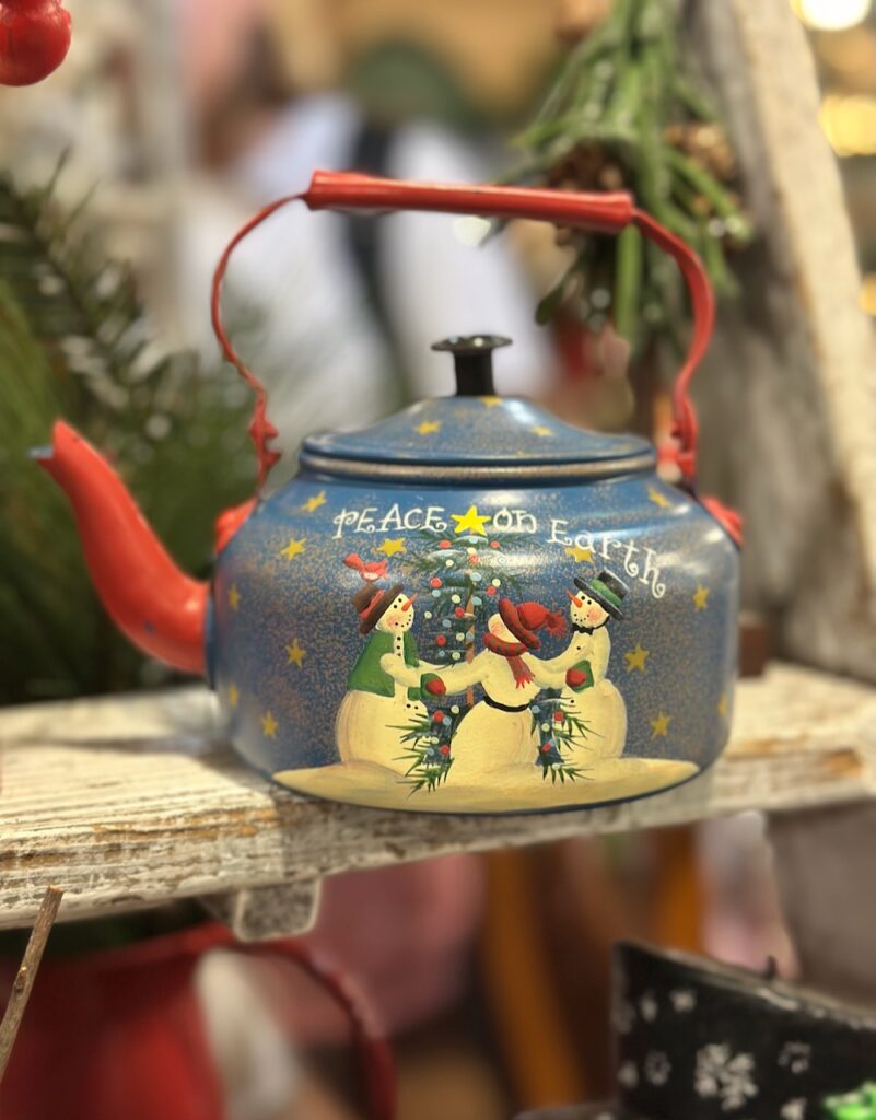 This is a decorated teapot with snow people that says, "Peace on Earth" to show eco friendly christmas decorations.