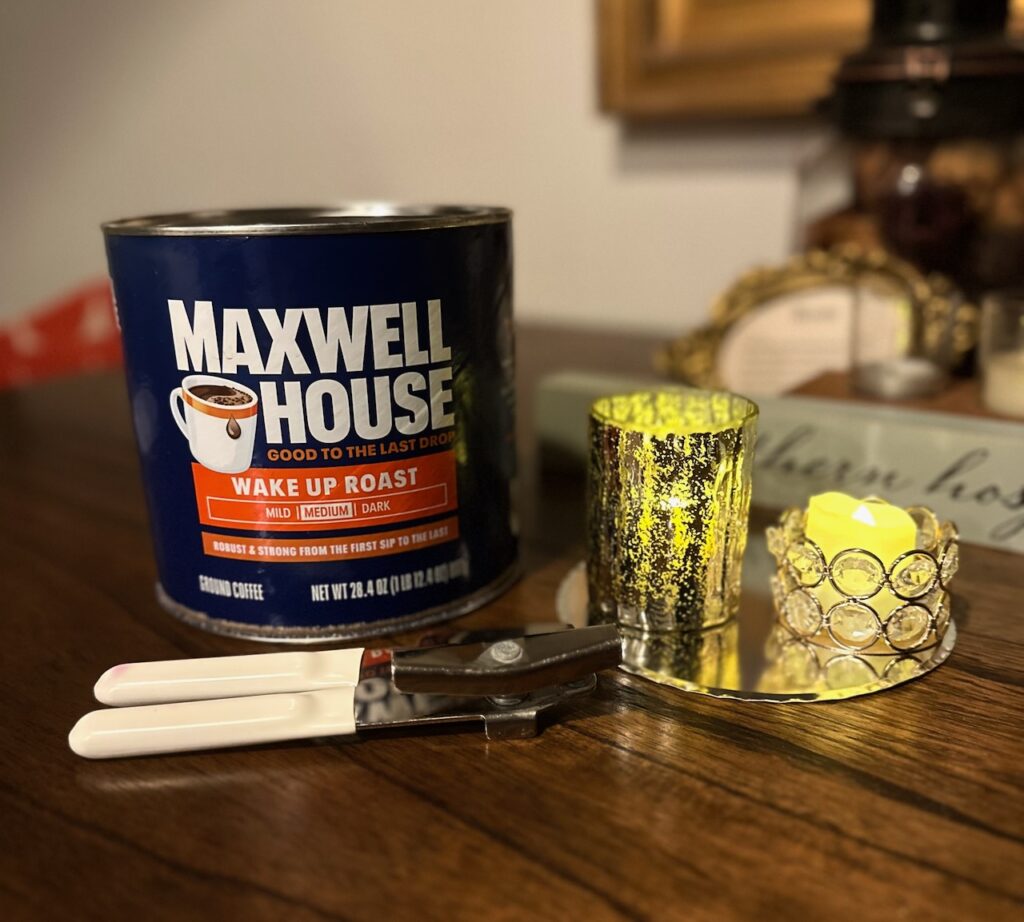 This is a Maxwell House coffee tin and two flameless candles sitting on the cutout of the tin's base to show sustainable christmas decorations to make.