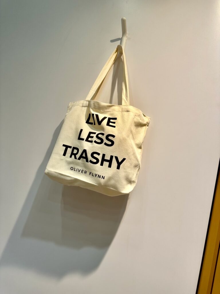This is a canvas tote bag by Oliver Flynn that says "Live less trashy" to talk about the problem with plastic.